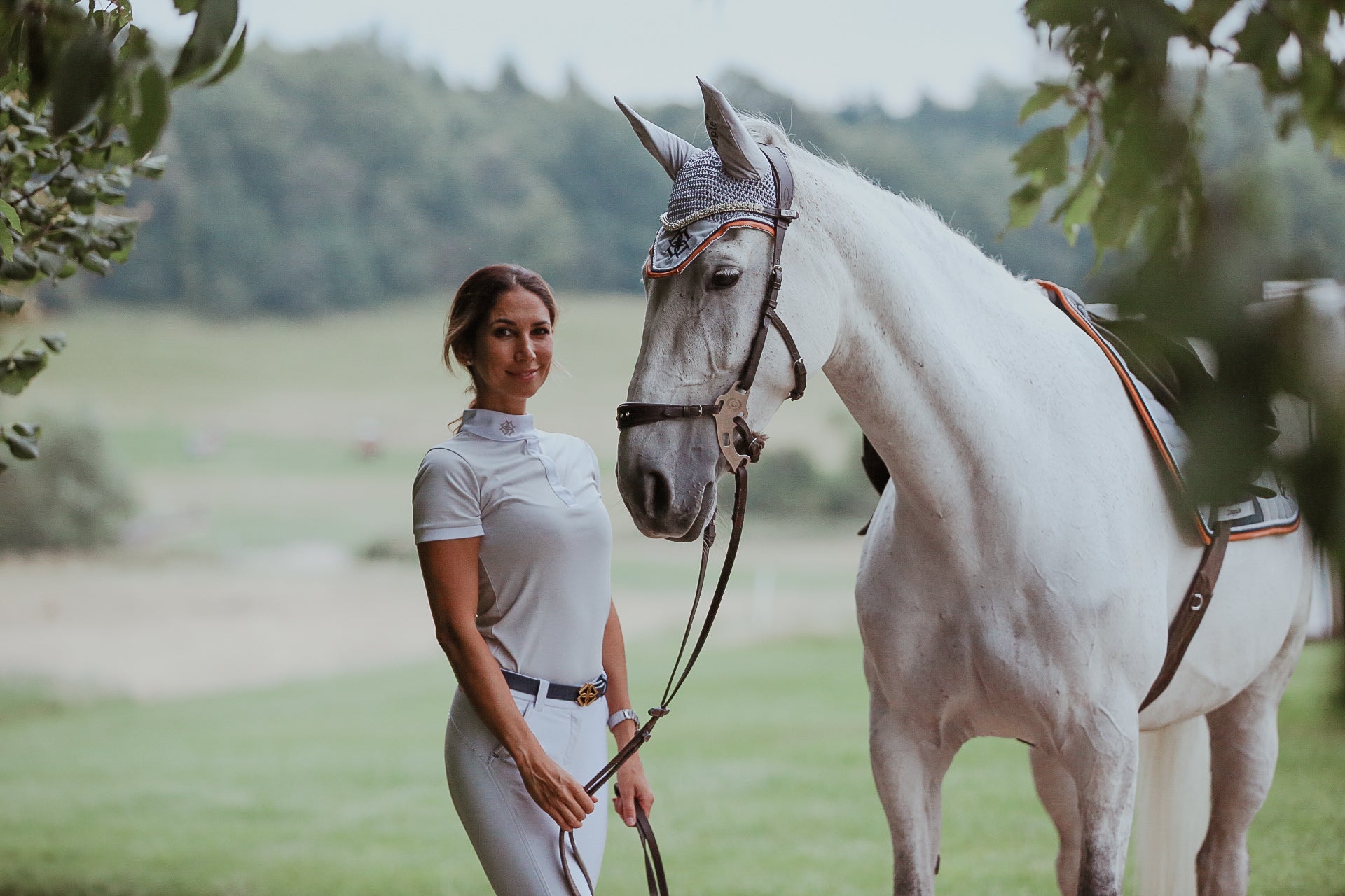 Dapple horse rider wearing Cloud Grey Show Shirt with horse wearing matching saddle pad and ear bonnet
