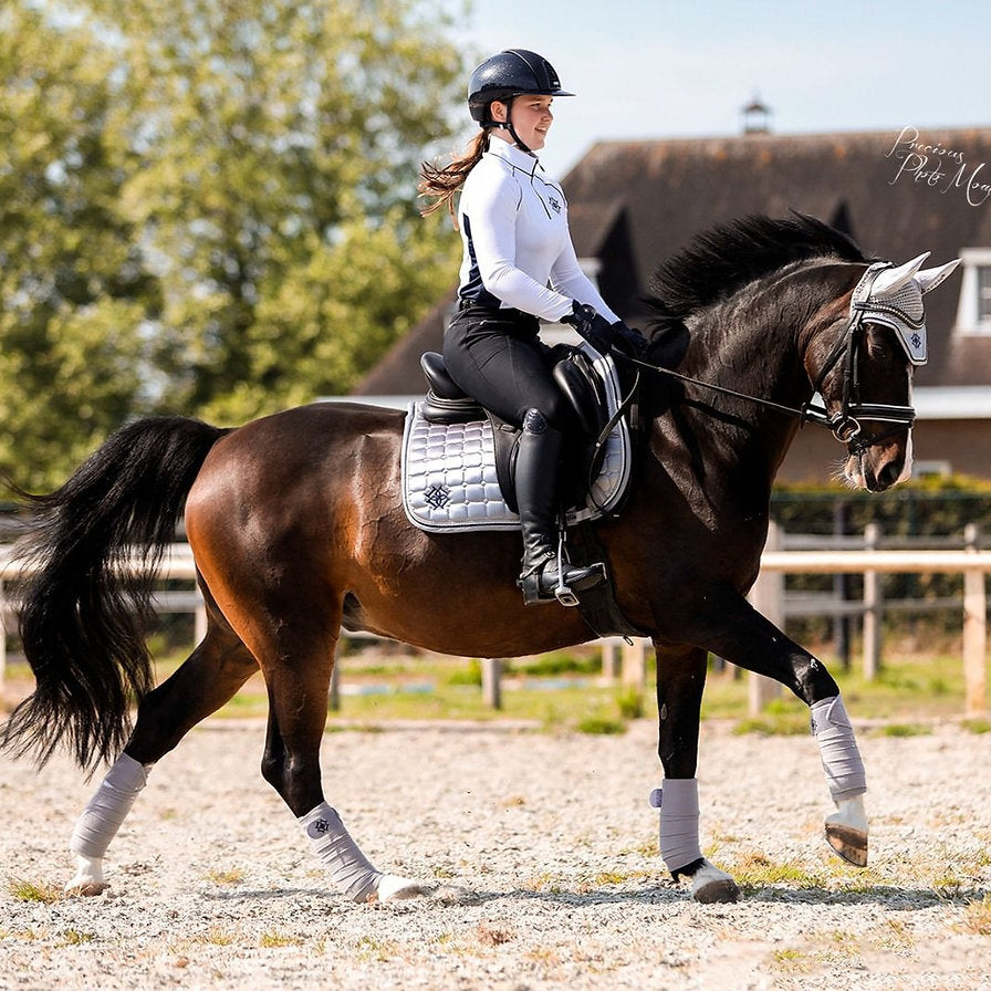 Dutch Rider Wendy Gebraad dressed in Dapple Equestrian baselayer on her horse dressed in the full matching Arctic Silver Set, Saddle Pad, Fly Veil and Fleece Bandages
