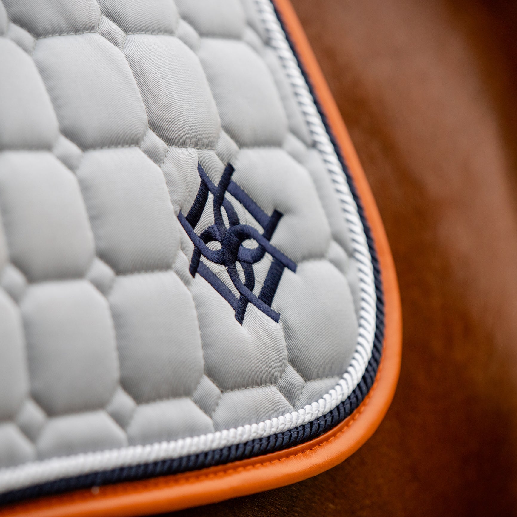 Close up of Dapple Equestrian Embroidered Logo on a Cloud Grey Saddle Pad