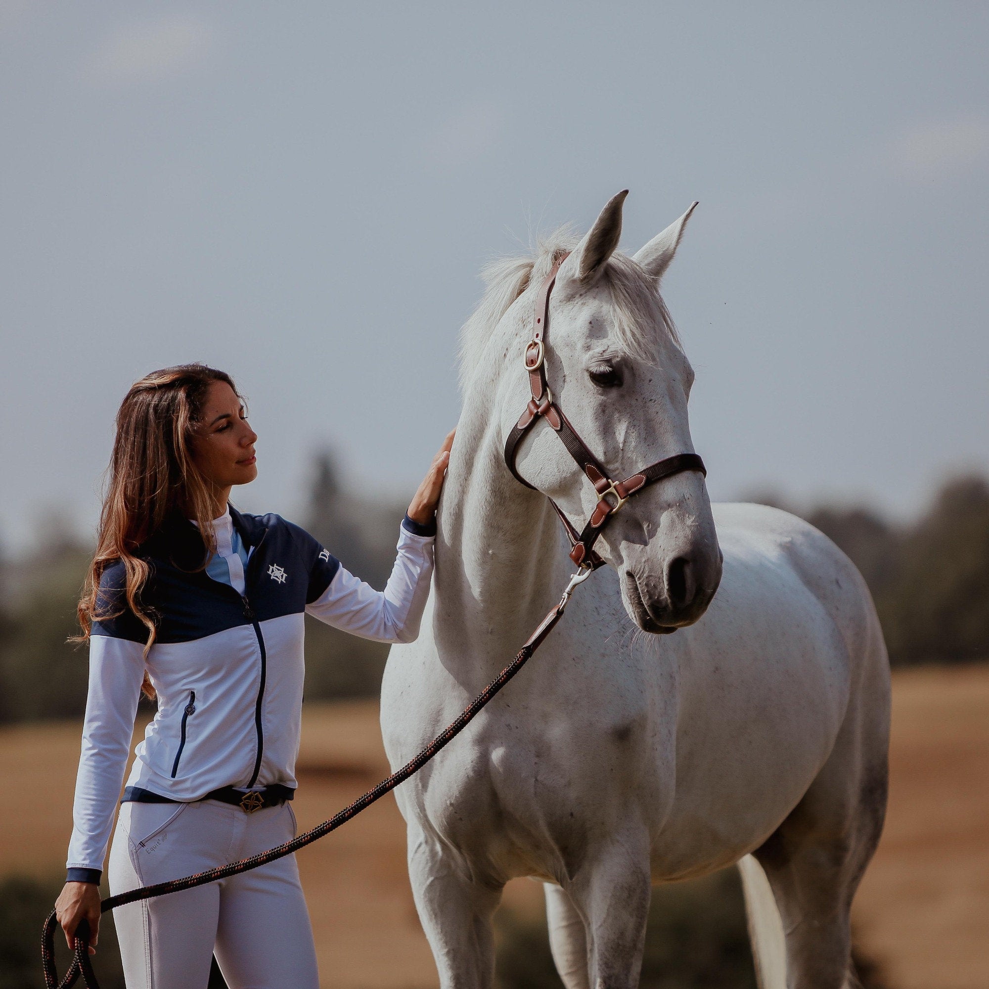 Dapple rider wearing Training Jacket and white horse wearing Head Collar and lead