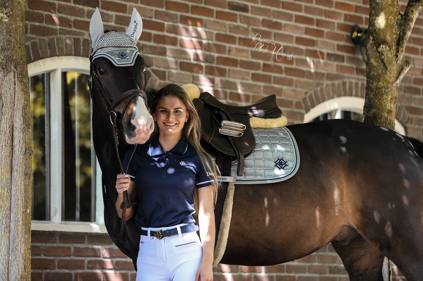 Horse wearing Arctic Silver Saddle Pad & Fly Veil with Horse rider standing in front of red brick wall