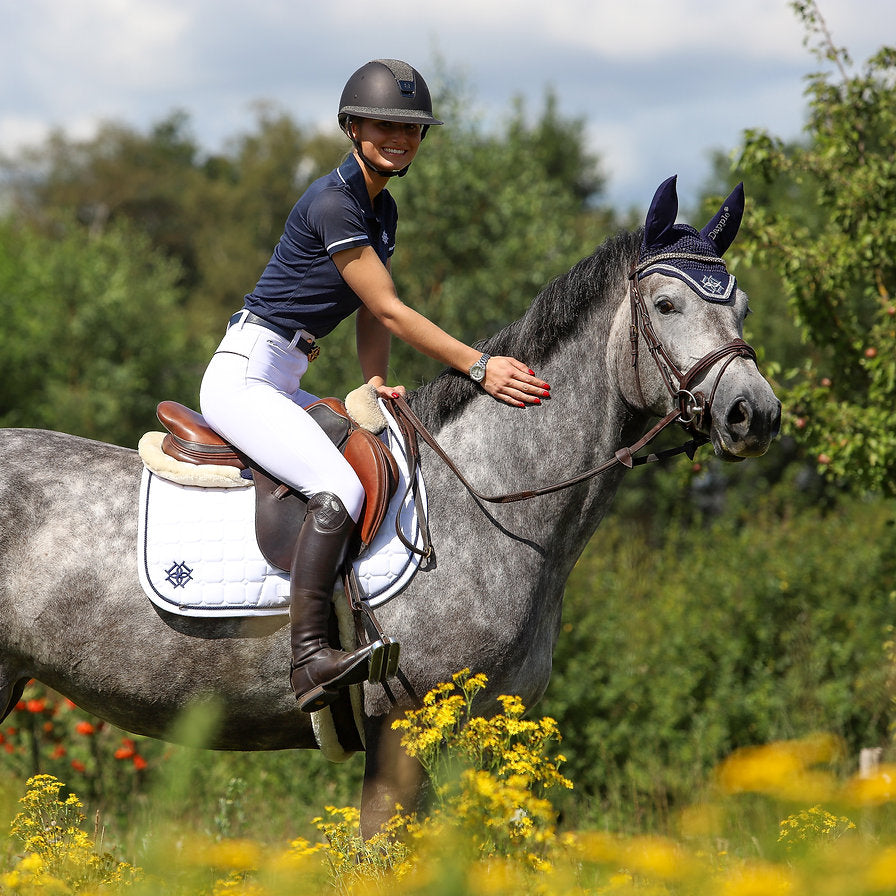 Showjumer Bibi Van Gehlen on a Dapple Grey horse wearing white jump saddle pad